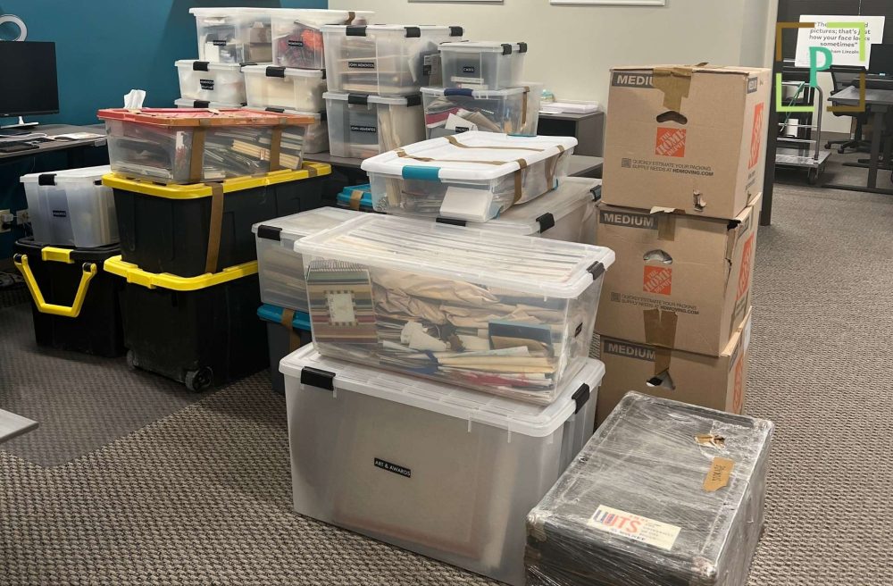 Photograph of boxes, storage bins, and photo organizing supplies in a workspace.